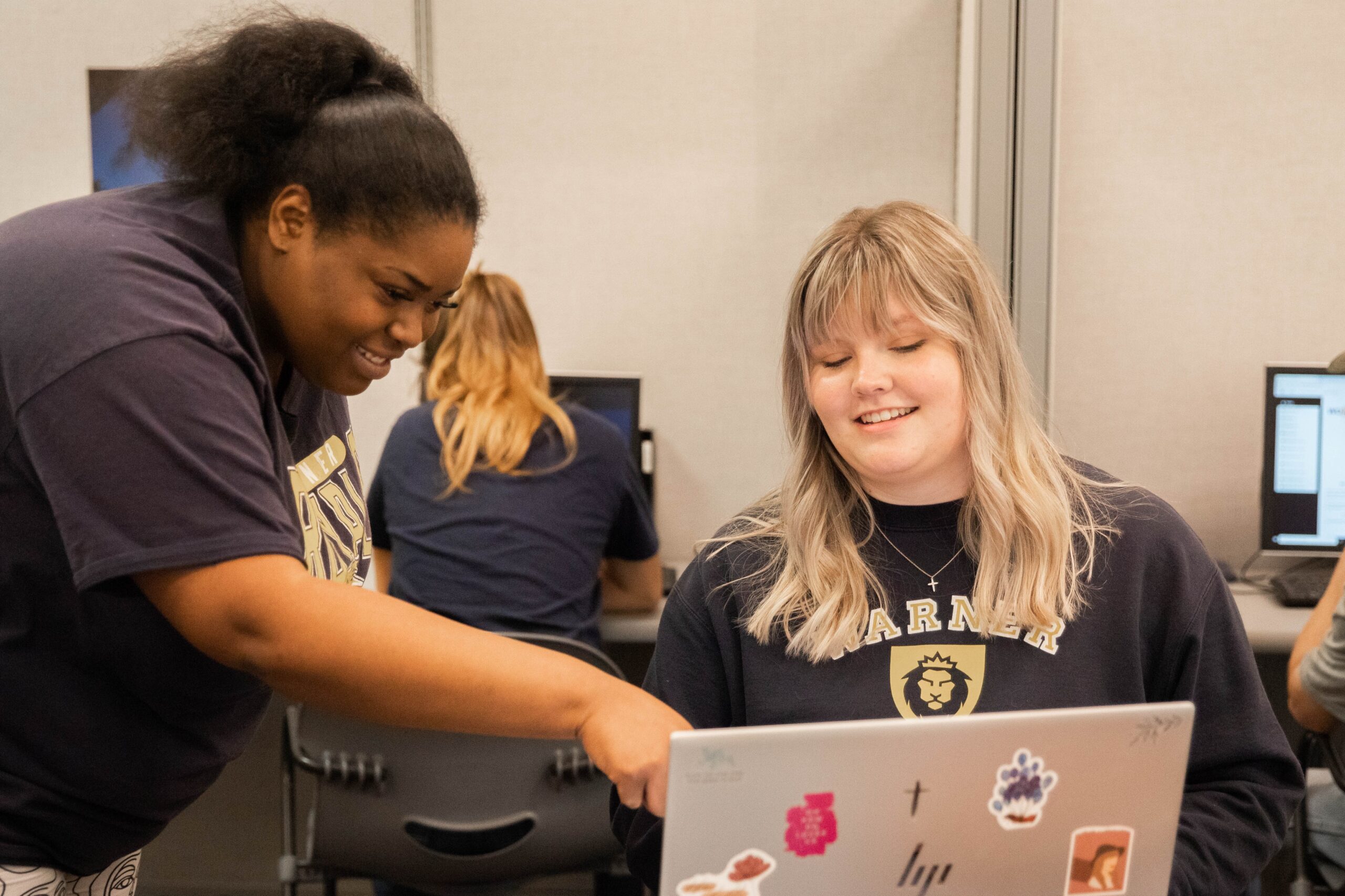 A student pointing to another student's laptop