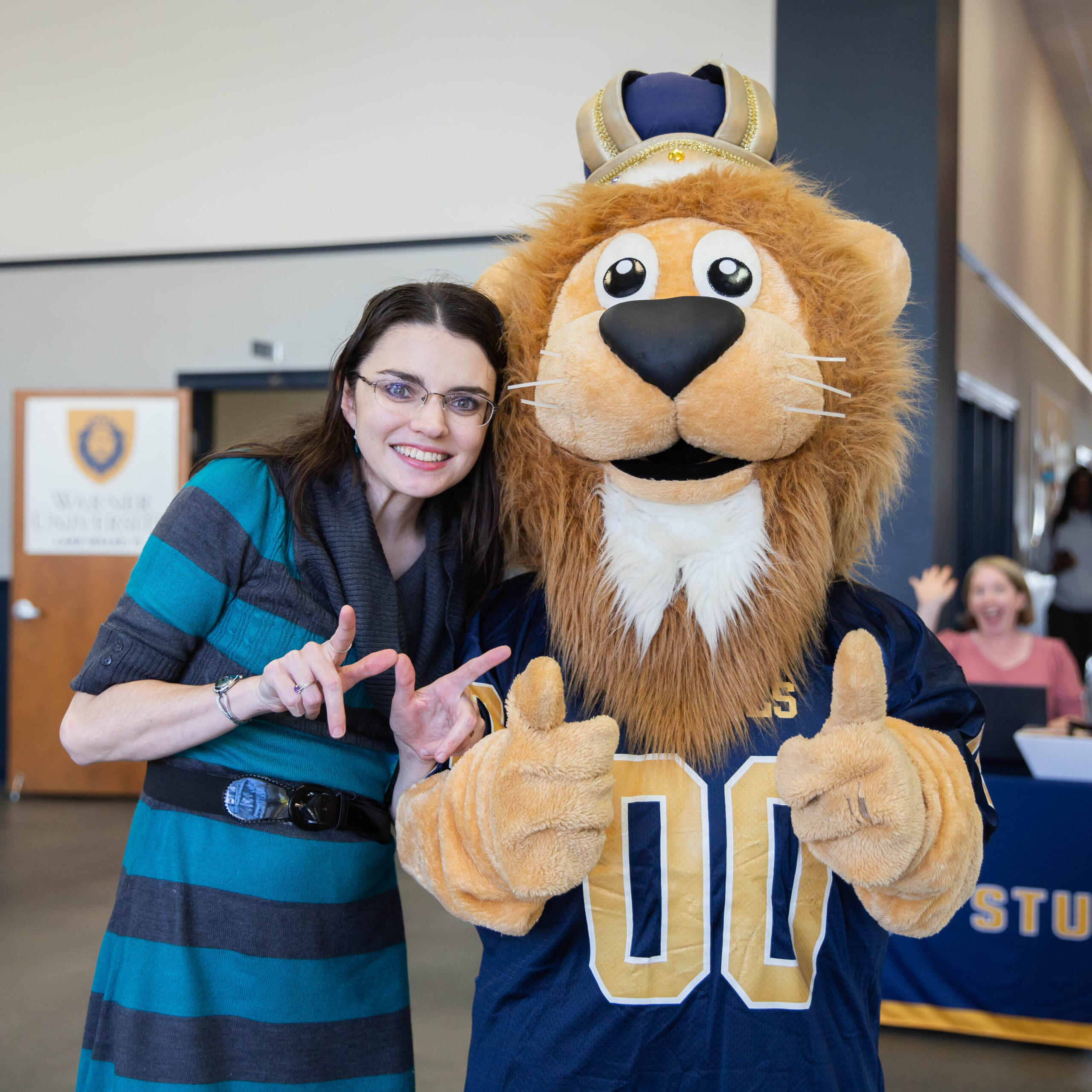 A lady and Duke the lion holding up the Royal W.