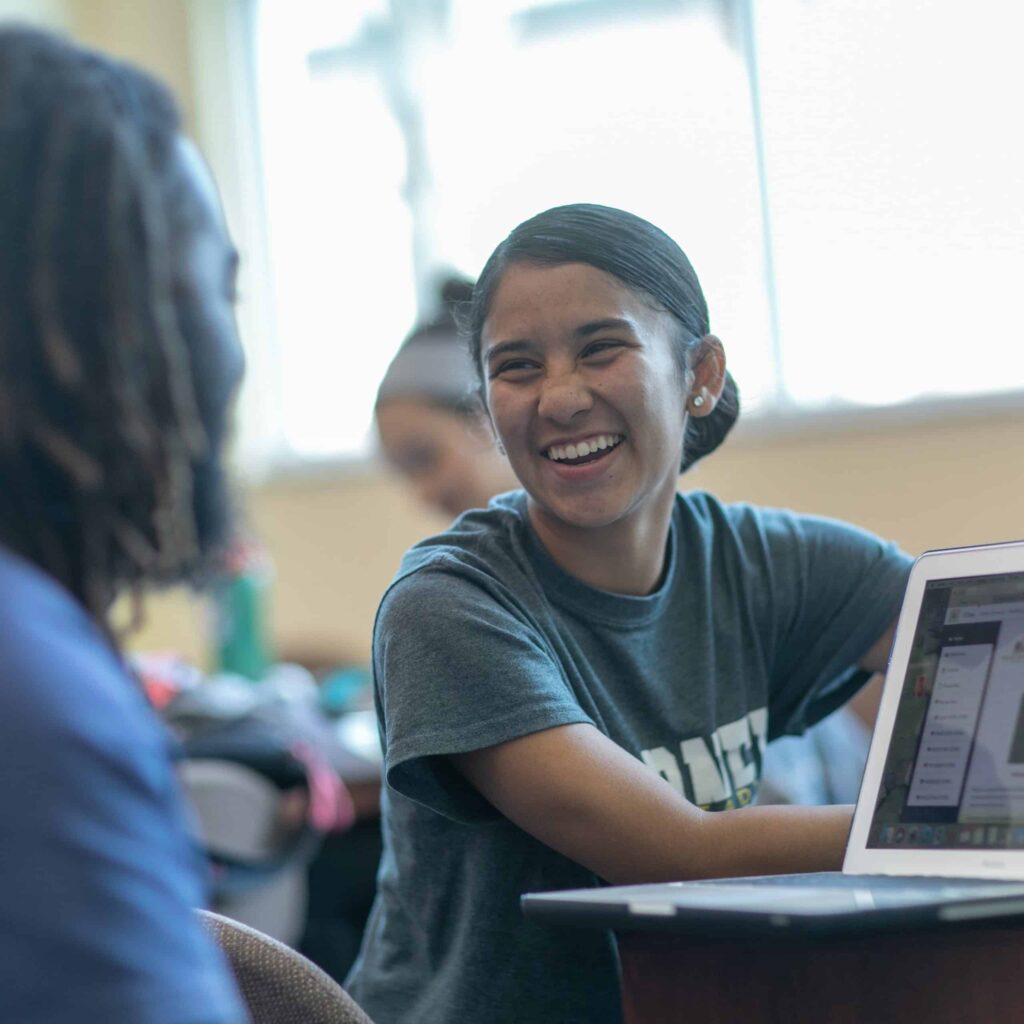 Girl laughing behind computer.